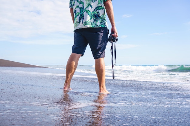 Homem irreconhecível com uma câmera de frente para o mar