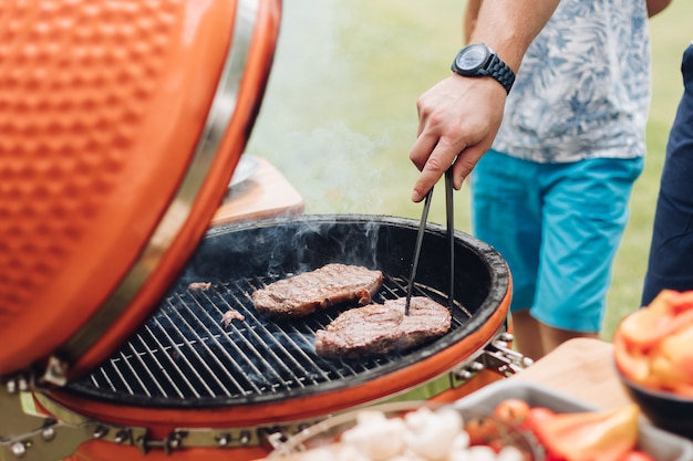 Homem irreconhecível, cozinhar carne na grelha.