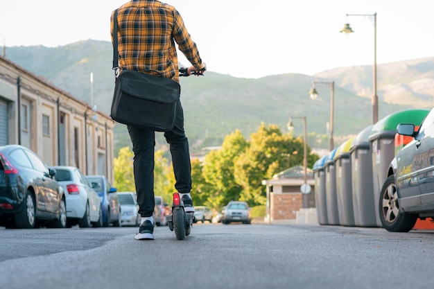 Homem irreconhecível em uma scooter elétrica em uma rua da cidade