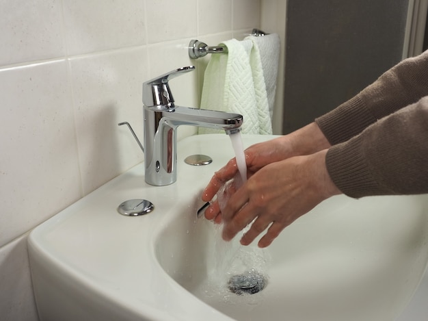 Homem irreconhecível lavando as mãos