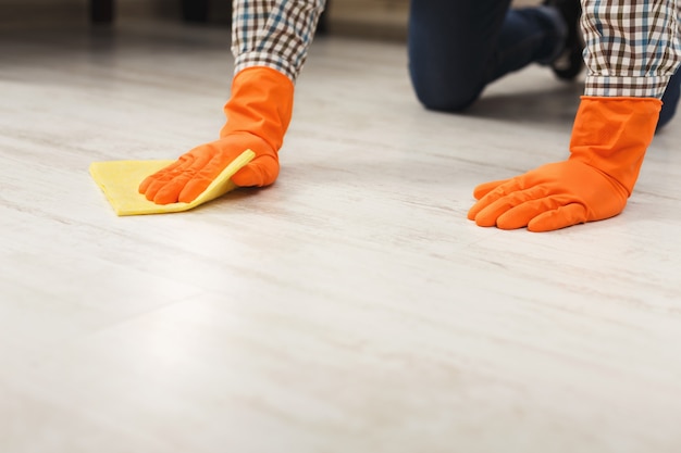Foto homem irreconhecível lavando o chão com toalha e detergentes na sala de estar. serviço de arrumação, limpeza doméstica e conceito de serviço de limpeza, espaço de cópia