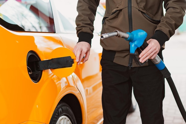 Homem irreconhecível, reabastecendo o carro do posto de gasolina, enchendo o combustível da gasolina benzina no carro no posto de gasolina Conceito de preços altos da gasolina