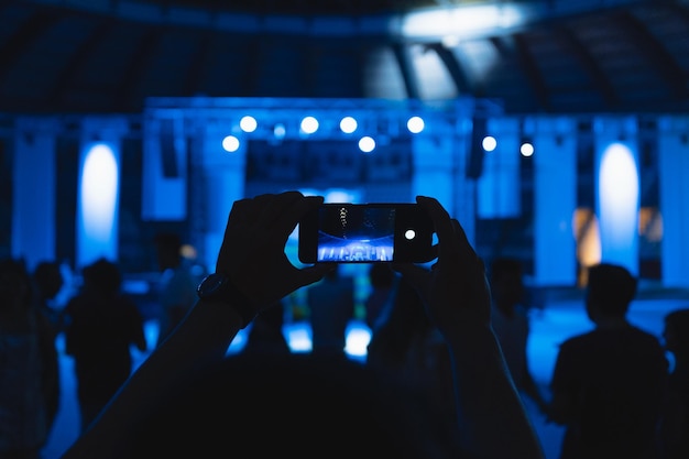 Foto homem irreconhecível tira uma foto com seu telefone em um concerto de música