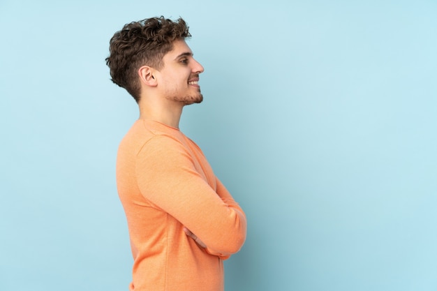 Homem isolado em fundo azul em posição lateral