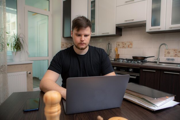 Homem isolado trabalhando na cozinha no escritório doméstico do laptop