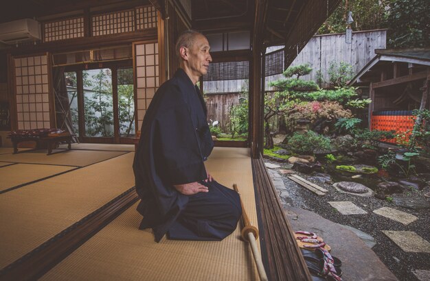 Homem japonês meditando em seu jardim