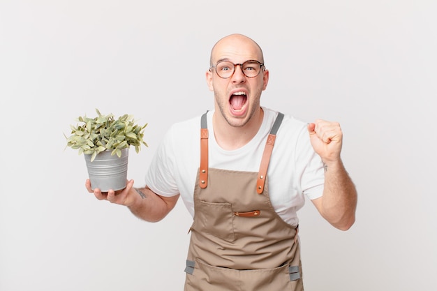 Homem jardineiro gritando agressivamente com uma expressão de raiva ou com os punhos cerrados celebrando o sucesso
