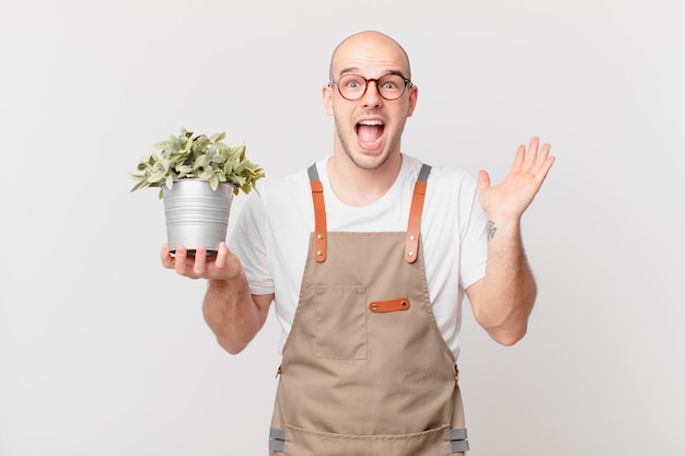 Homem jardineiro se sentindo feliz, animado, surpreso ou chocado, sorrindo e surpreso com algo inacreditável