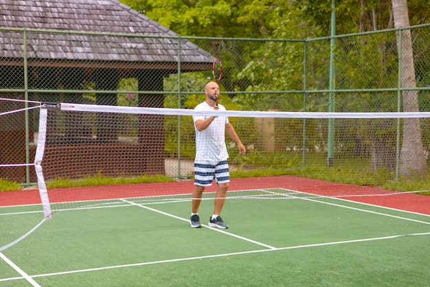 homem joga badminton ao ar livre no ar fresco lança um ônibus e segura uma raquete uma ilha nas Maldivas recreação ativa e esportes.