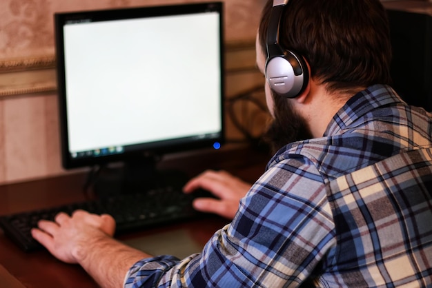 Homem joga computador com fones de ouvido