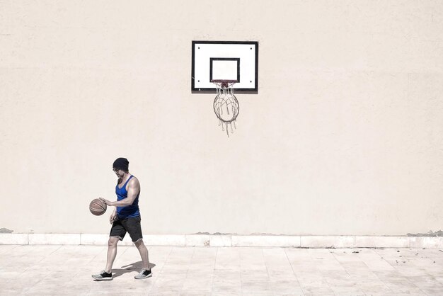 Homem jogando basquete na quadra durante um dia ensolarado