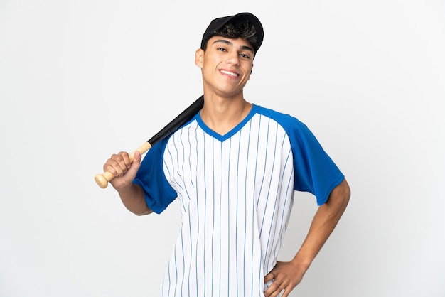 Homem jogando beisebol na parede branca isolada, posando com os braços na cintura e sorrindo