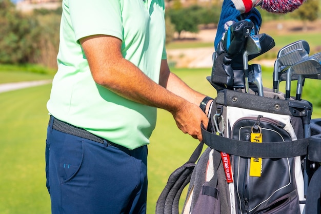 Homem jogando golfe pegando o saco de tacos e colocando-o no carrinho