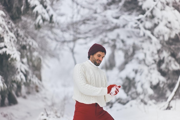 Homem jogando jogo de inverno jogando bola de neve em uma floresta montanhosa ao ar livre