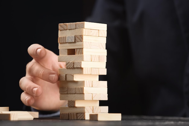 Homem jogando jogo de jenga no conceito de gerenciamento de mesa