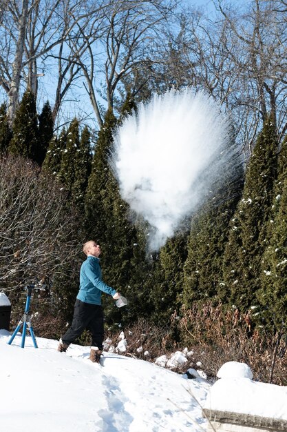 Foto homem jogando neve enquanto está perto de árvores durante o inverno