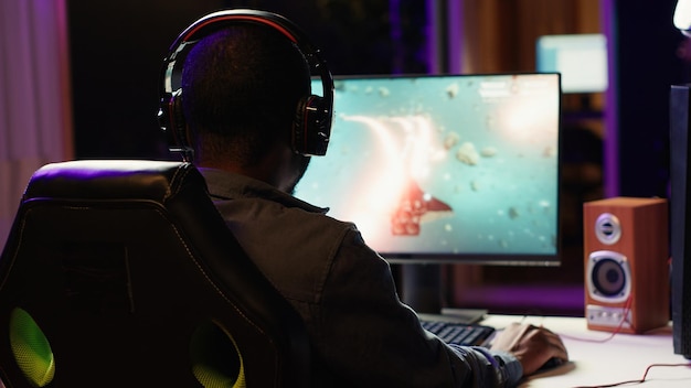 Homem jogando videogame espacial de ficção científica na tela do PC em uma sala escura