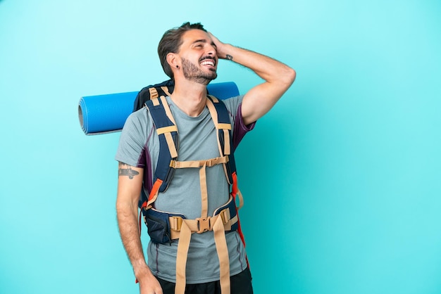 Homem jovem alpinista com uma mochila grande isolada em fundo azul percebeu algo e pretende a solução