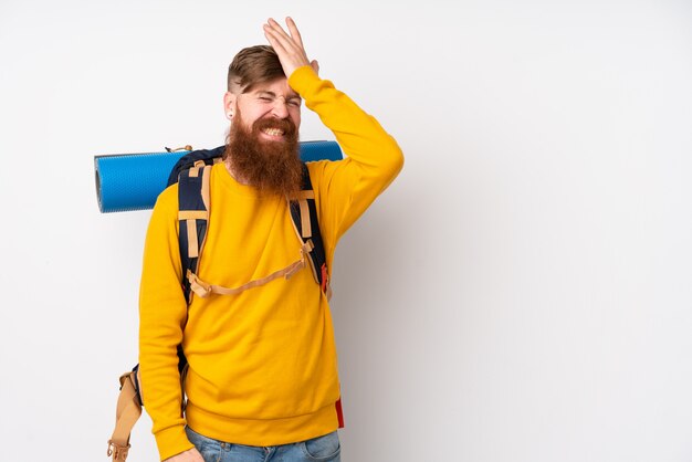 Homem jovem alpinista com uma mochila grande sobre parede branca isolada, tendo dúvidas com a expressão do rosto confundir