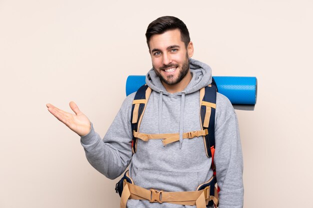 Homem jovem alpinista com uma mochila grande sobre parede isolada