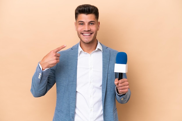 Homem jovem apresentador de TV caucasiano isolado no fundo branco dando um polegar para cima gesto