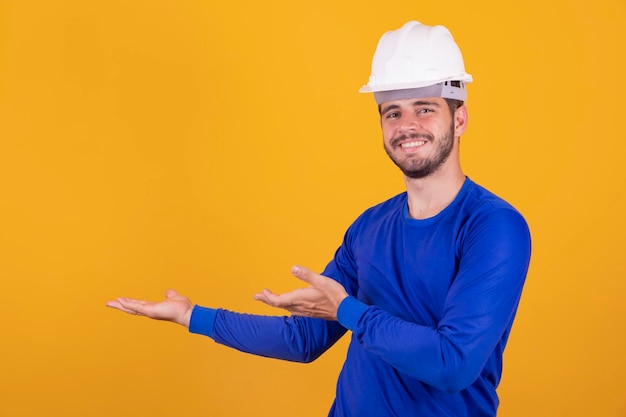 Homem jovem arquiteto com capacete apontando para o lado