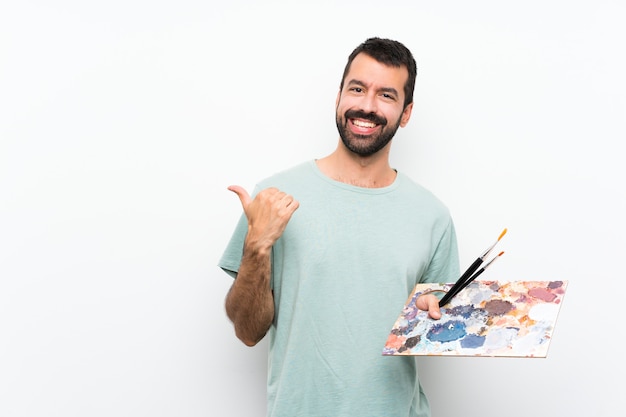 Homem jovem artista segurando uma paleta apontando para o lado