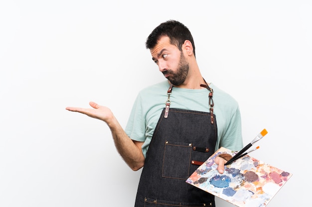 Foto homem jovem artista segurando uma paleta com dúvidas