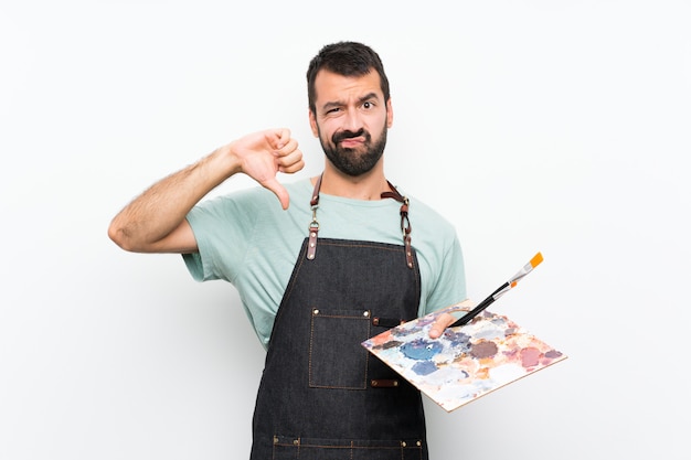 Foto homem jovem artista segurando uma paleta mostrando o polegar para baixo