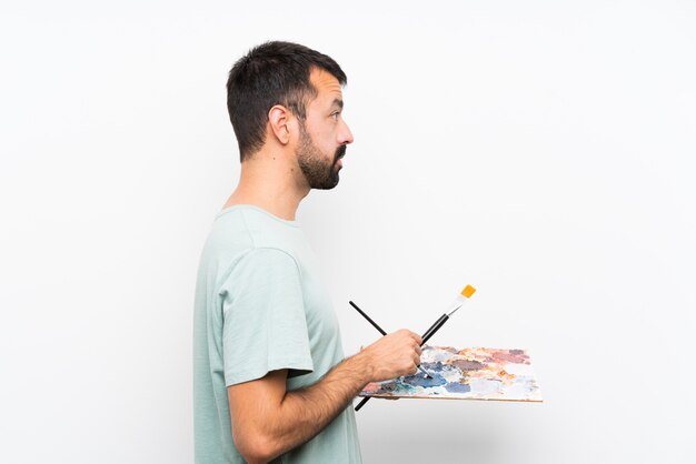 Homem jovem artista segurando uma paleta sobre fundo isolado