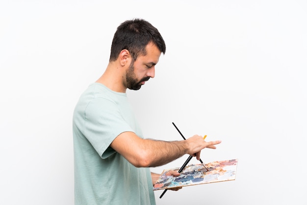 Foto homem jovem artista segurando uma paleta sobre parede isolada