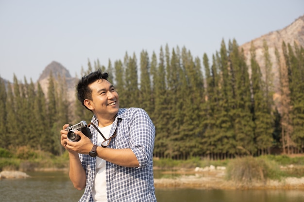 Homem jovem asiático na camisa azul com cachorro fofo acampar na vista da montanha do lago colina feliz e aproveitar a vida