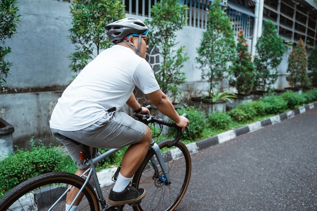 Homem jovem asiático vestindo capacetes de bicicleta ao andar de bicicleta