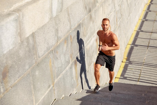 Homem jovem atleta faz corrida matinal Macho sobe as escadas fazendo exercícios cardio