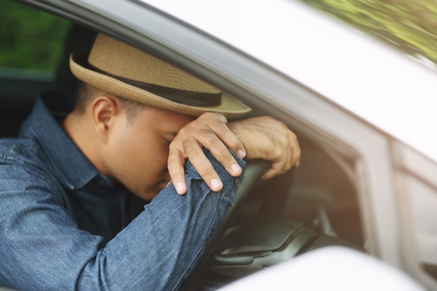 Homem jovem bêbado, caído no volante, está cansado de dormir ao dirigir o carro. conceito sonolento durante a viagem de condução, não conduza.