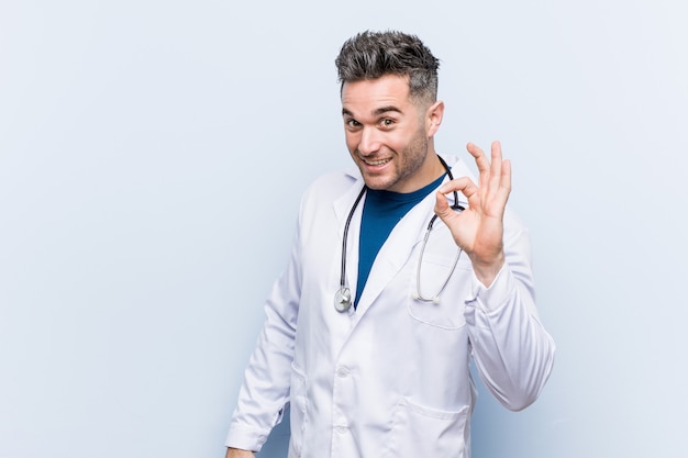 Foto homem jovem bonito médico alegre e confiante mostrando okey gesto.