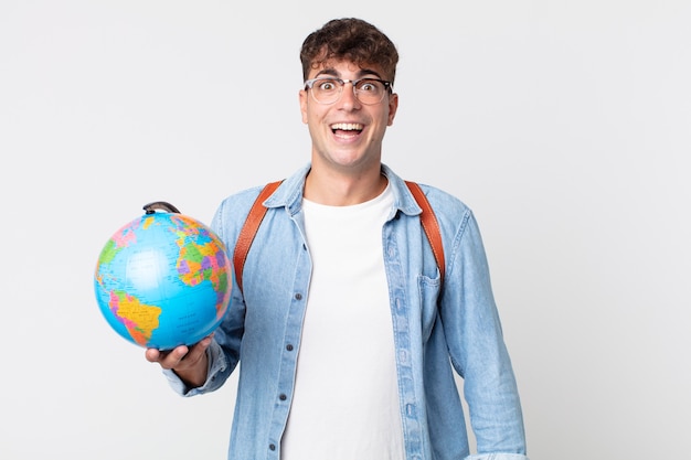 Homem jovem bonito parecendo feliz e agradavelmente surpreso. estudante segurando um mapa do globo