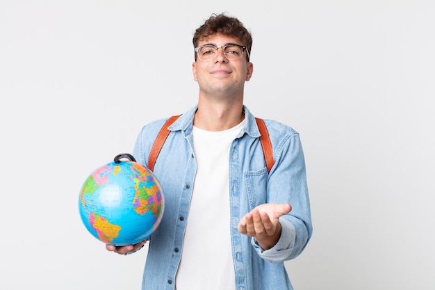 Homem jovem bonito sorrindo alegremente com simpáticos e oferecendo e mostrando um conceito. estudante segurando um mapa do globo