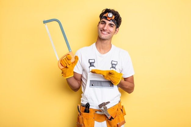 Homem jovem bonito sorrindo alegremente, sentindo-se feliz e mostrando um conceito. conceito de conserto de faz-tudo