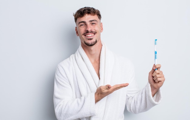 Homem jovem bonito sorrindo alegremente, sentindo-se feliz e mostrando um conceito. conceito de escova de dentes