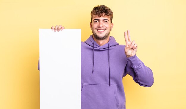 Homem jovem bonito sorrindo e parecendo amigável, mostrando o número dois. copie o conceito de espaço