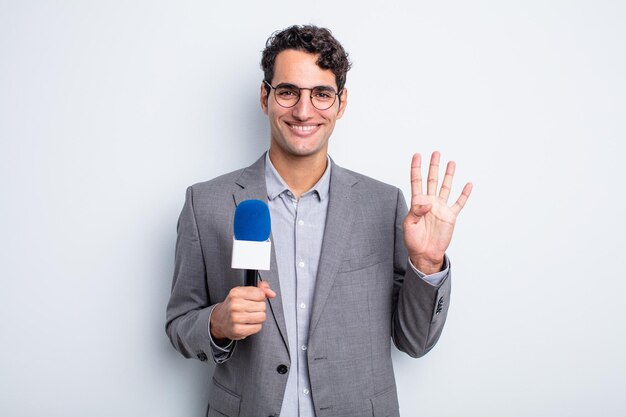 Homem jovem bonito sorrindo e parecendo amigável, mostrando o número quatro. apresentador com microfone