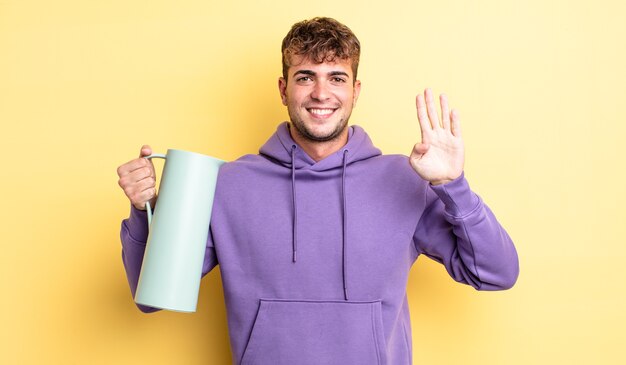 Homem jovem bonito sorrindo e parecendo amigável, mostrando o número quatro. conceito de garrafa térmica