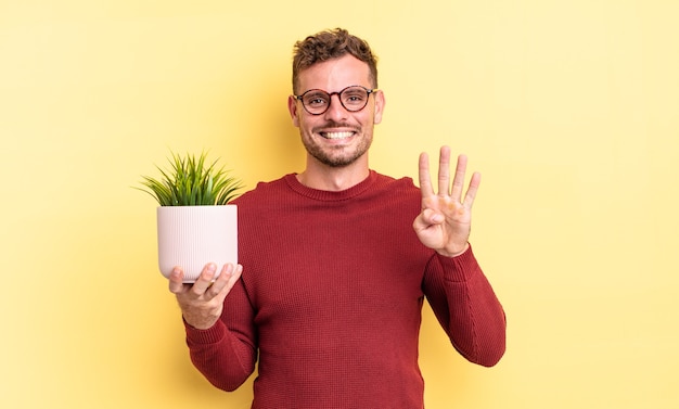 Homem jovem bonito sorrindo e parecendo amigável, mostrando o número quatro. conceito de planta decorativa