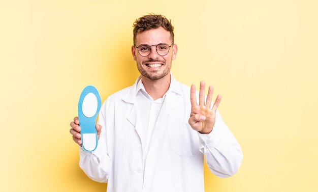 Homem jovem bonito sorrindo e parecendo amigável, mostrando o número quatro. conceito de quiropodista