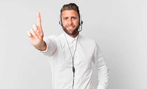 Homem jovem bonito sorrindo e parecendo amigável, mostrando o número um. conceito de telemarketing