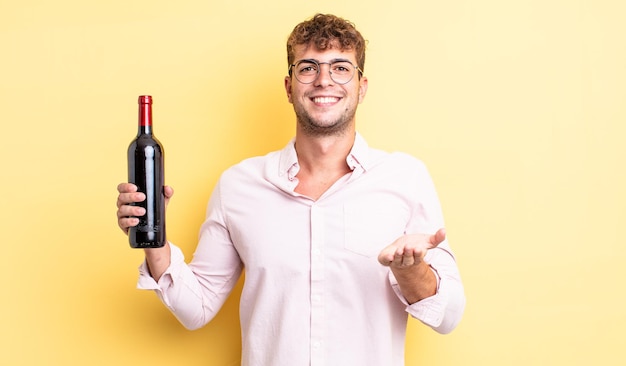 Homem jovem bonito sorrindo feliz com simpáticos e oferecendo e mostrando um conceito. conceito de garrafa de vinho