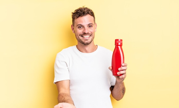 Homem jovem bonito sorrindo feliz com simpáticos e oferecendo e mostrando um conceito. conceito de ketchup