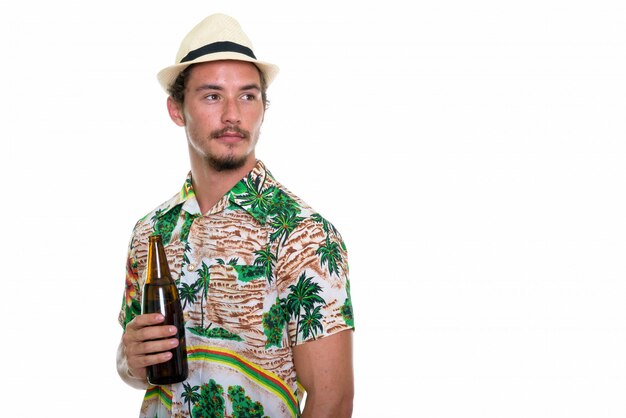 Homem jovem bonito turista pensando enquanto segura uma garrafa de cerveja