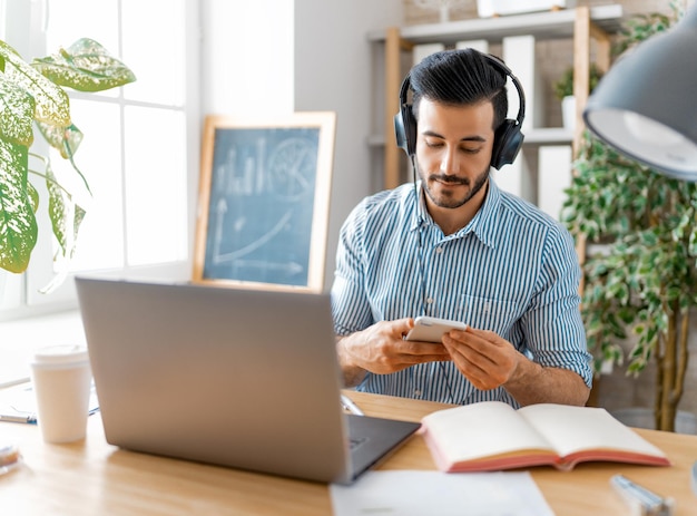 Homem jovem casual feliz trabalhando em um laptop em casa.